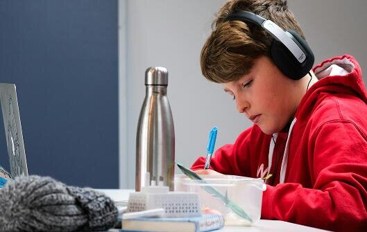 Osoba siedząca przy oknie, uśmiechnięta.